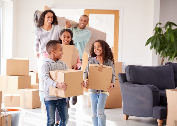 Smiling Family Carrying Boxes Into New Home On Moving Day Smiling Family Carrying Boxes Into New Home On Moving Day